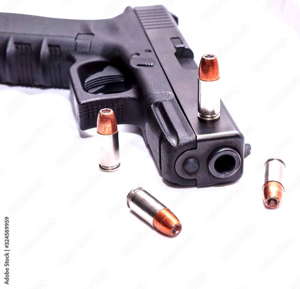 A black 9mm pistol with four 9mm hollow point bullets on and around it on a white background A black 9mm pistol with four 9mm hollow point bullets on and around it on a white background