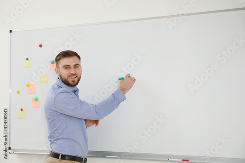 Obraz na plátně Young teacher writing on whiteboard in classroom. Space for text