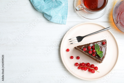 Delicious chocolate cake with red currants on white wooden table, flat lay. Space for text