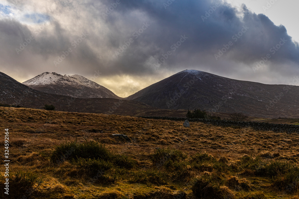 Snow capped Slieve Bearnagh and Slieve Meelmore backlit in the Mourne mountains, Newcastle County Down, Northern Ireland