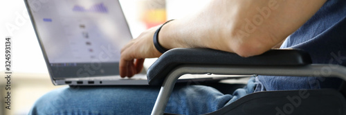 Foto Man sitting in wheelchair working with laptop computer