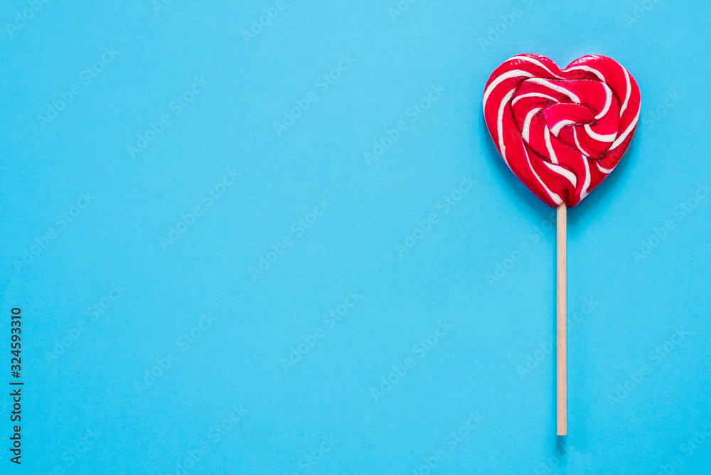 red heart-shaped lollipop on a blue background