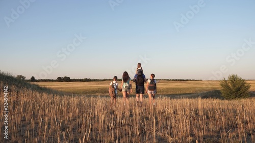 children and father and mother with backpacks travel through valley. Dad mom with daughters go camping. Family of tourists traveling. teamwork of tourists. movement to victory.