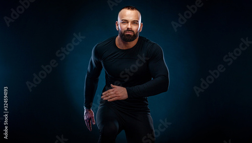 Muscular young fitness sports man athlete in compression garment. Workout in gym photo