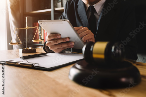 Justice and law concept.Male judge in a courtroom with the gavel, working with, computer and  docking keyboard, eyeglasses, on table in morning light