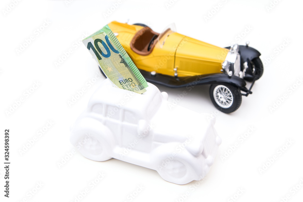 The ceramic car shaped money box with a banknote inside with model car behind. It can be symbol for costs for car´s repairs, investment, savings or insurance. The ceramic car shaped money box with a banknote inside with model car behind. It can be symbol for costs for car´s repairs, investment, savings or insurance.