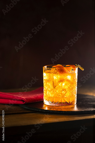 Glass of the cocktail negroni on a old wooden board. Drink with gin, campari martini rosso and orange, an italian cocktail, an aperitif, first mixed in Firenze Italy in 1919 alcoholic bitter cocktail