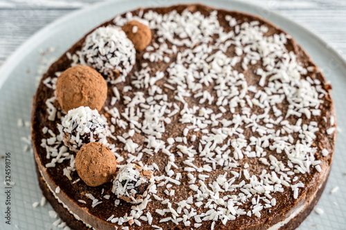 chocolate cake on a plate. Chocolate and coconut cake on a white wooden background. Foodfoto in a high key. Raw dessert