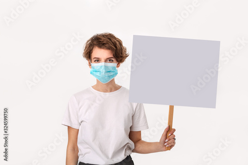 Worried woman wearing blue medical mask holds picket sign with copy space and piniting at her head photo