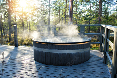 Modern big barrel outdoor hot tub in the middle of forest. The hot tub's soothing warm water relaxes muscles and eases tensions, so your worries can simply melt away.