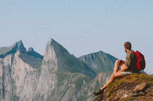Man relaxing in mountains enjoying view adventure travel vacations outdoor traveler sitting on cliff healthy lifestyle trekking in Norway © EVERST