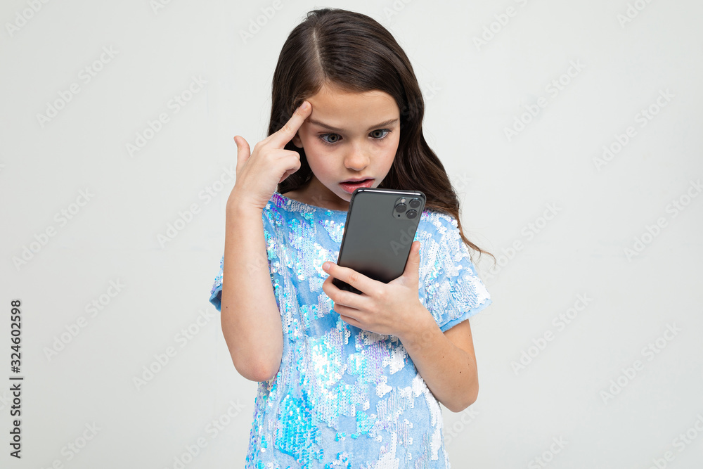 surprised teenager girl emotionally looks at the phone on a white studio background surprised teenager girl emotionally looks at the phone on a white studio background