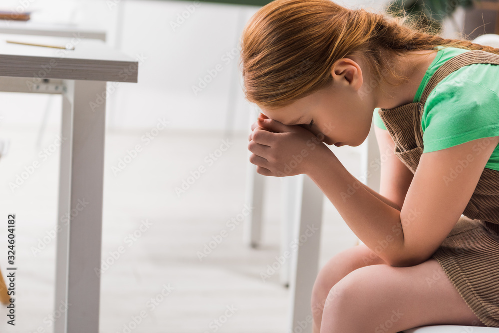 frustrated and bullied schoolgirl sitting in classroom