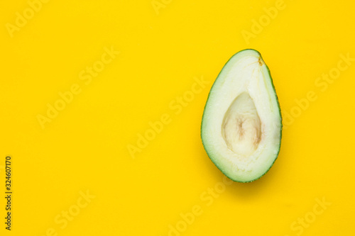 Halve of avocado on a yellow background. Top view. Copy, empty space for text