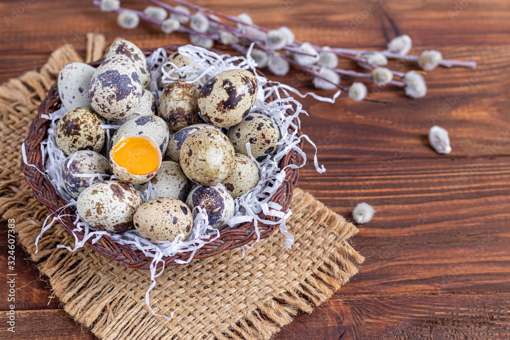 Quail eggs are placed in a wicker basket next to a willow twig. Getting ready for Easter. On a wooden background. Quail eggs are placed in a wicker basket next to a willow twig. Getting ready for Easter. On a wooden background.