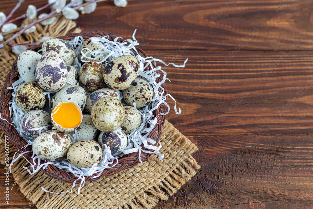 Quail eggs are placed in a wicker basket next to a willow twig. Getting ready for Easter. On a wooden background. Quail eggs are placed in a wicker basket next to a willow twig. Getting ready for Easter. On a wooden background.