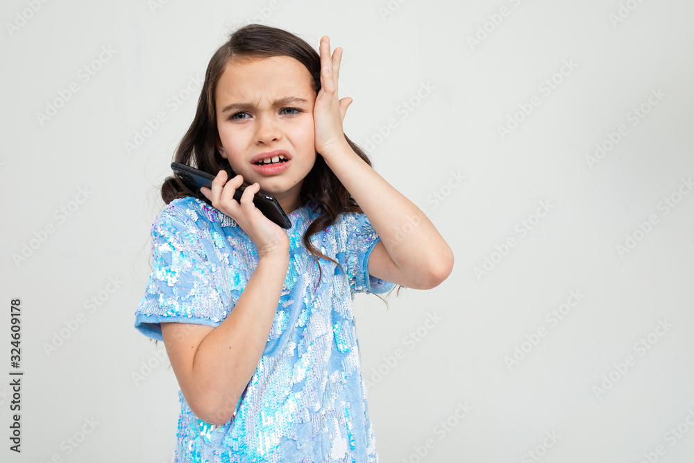 indignant teenager girl carefully talking on the phone in an interlocutor and holding her head on a white background with copy space indignant teenager girl carefully talking on the phone in an interlocutor and holding her head on a white background with copy space