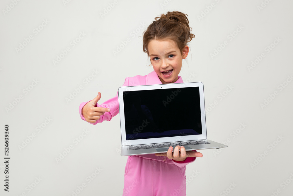Closeup portrait of an attractive young girl in a pink suit showing a laptop screen with a mockup on a white background Closeup portrait of an attractive young girl in a pink suit showing a laptop screen with a mockup on a white background