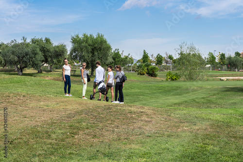 Group of young people standing on a golf course with a golf cart © carles