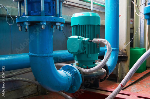 Green vertical motors with pumps on a blue colored water pipeline.