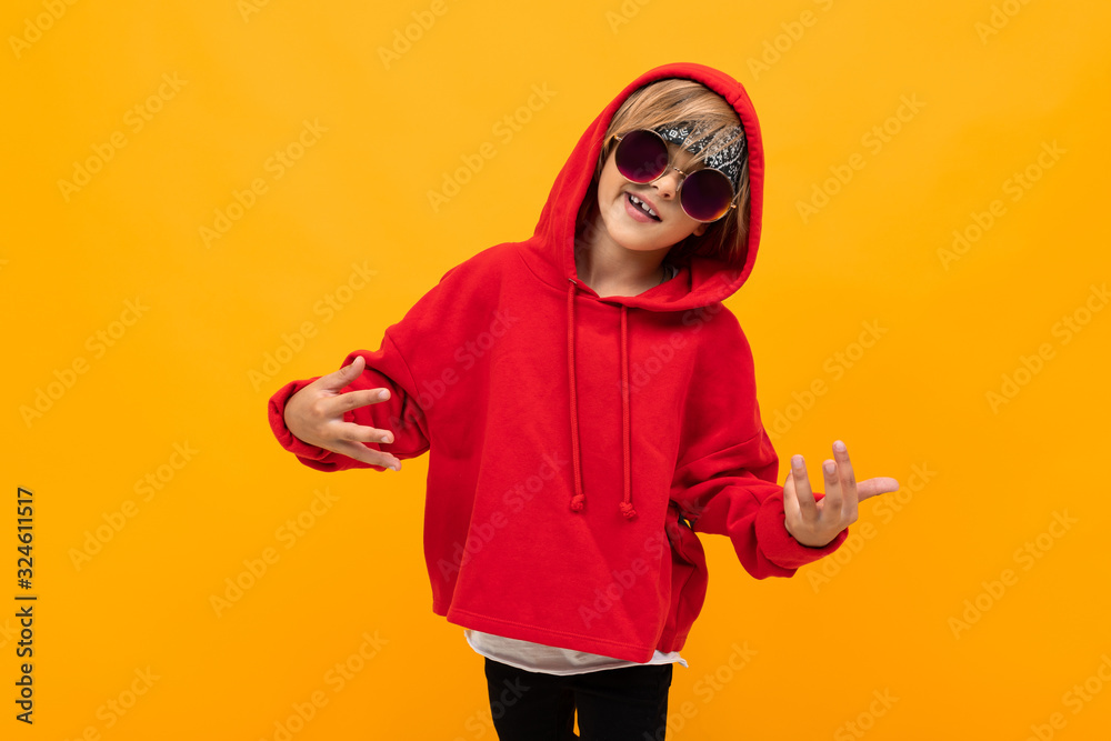 Stylish young boy in red sweatshirt and white t-shirt puts hands on his chest Stylish young boy in red sweatshirt and white t-shirt puts hands on his chest