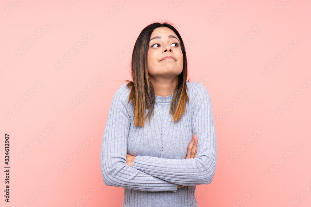 Woman over isolated pink background making doubts gesture while lifting the shoulders Woman over isolated pink background making doubts gesture while lifting the shoulders