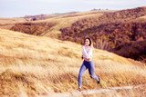 Woman in sportware running in the nature with dry grass and glade on background