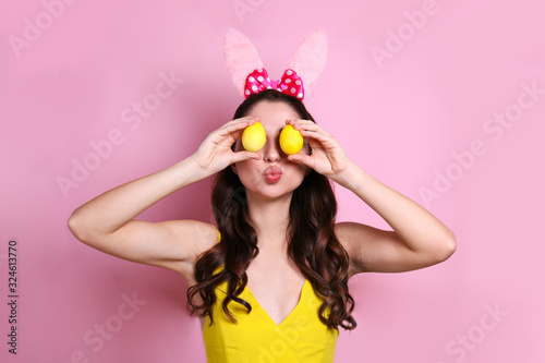 Photography Studio portrait of young beautiful woman wearing traditional bunny ears headband for easter and smiling