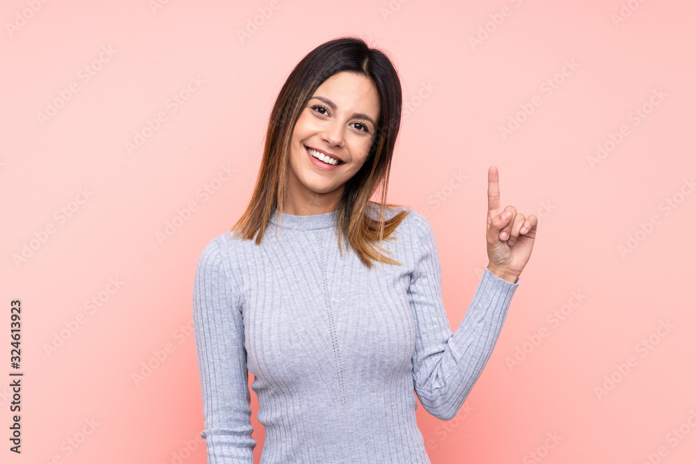 Woman over isolated pink background showing and lifting a finger in sign of the best