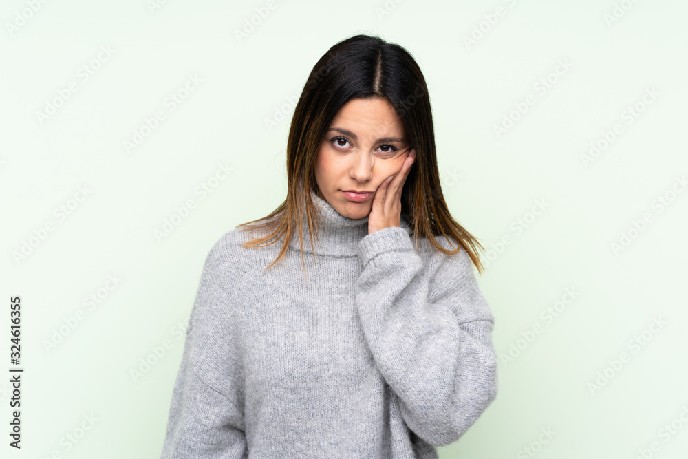 Woman wearing a sweater over isolated green background unhappy and frustrated Woman wearing a sweater over isolated green background unhappy and frustrated