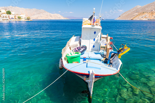 Fototapeta Naklejka Na Ścianę i Meble -  small fishing boat on crystal clear water of Symi island coast in Greece