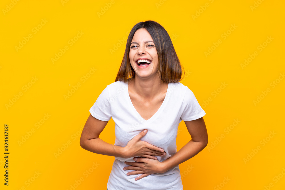Obraz premium Young woman over isolated yellow background smiling a lot