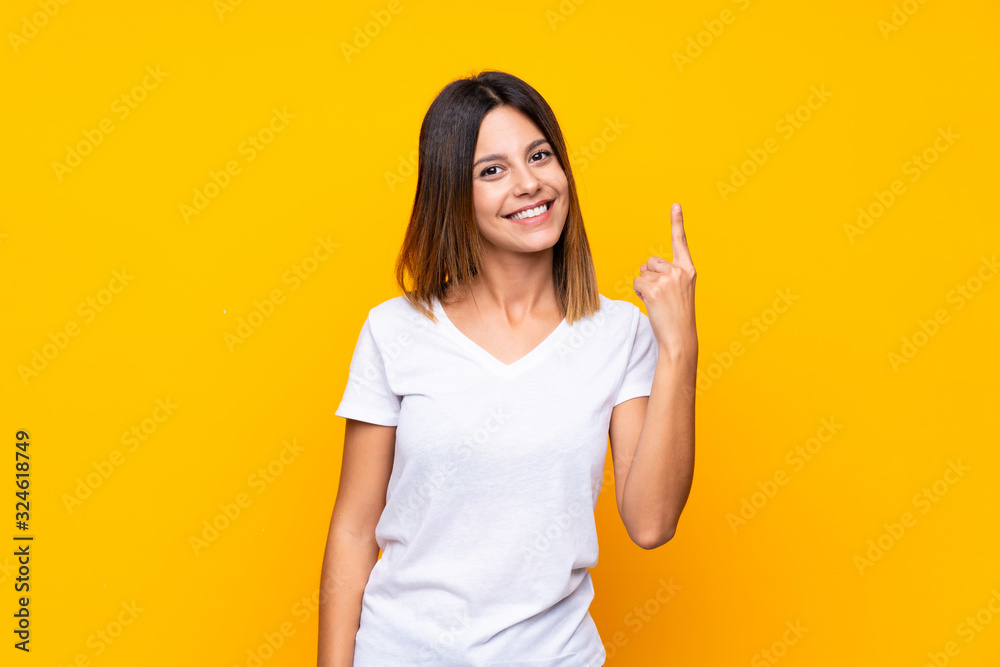 Young woman over isolated yellow background showing and lifting a finger in sign of the best Young woman over isolated yellow background showing and lifting a finger in sign of the best
