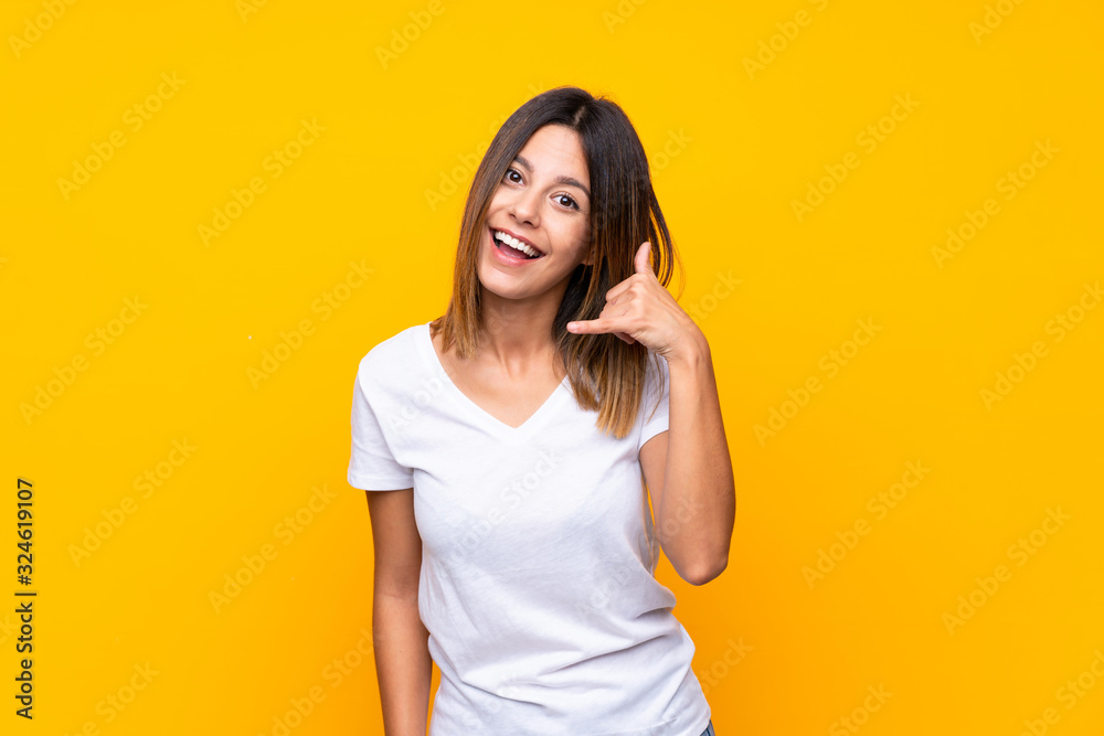 Young woman over isolated yellow background making phone gesture. Call me back sign Young woman over isolated yellow background making phone gesture. Call me back sign