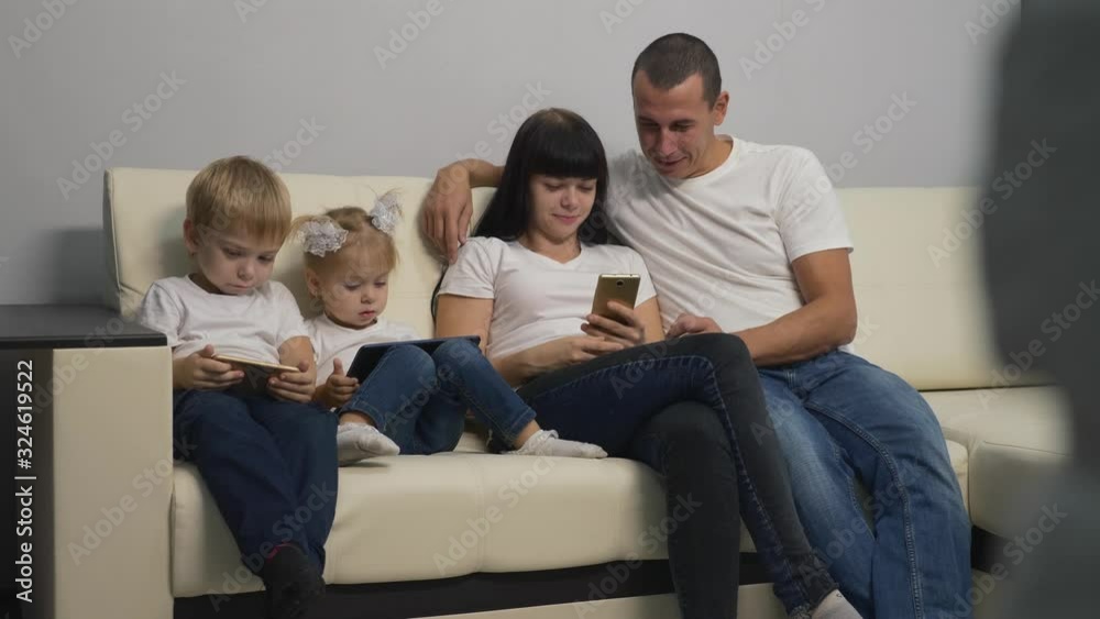 Happy family sitting on the couch, having fun making purchases in the online store.Working together, mom dad and kids enjoy modern technology at home. Happy family sitting on the couch, having fun making purchases in the online store.Working together, mom dad and kids enjoy modern technology at home.