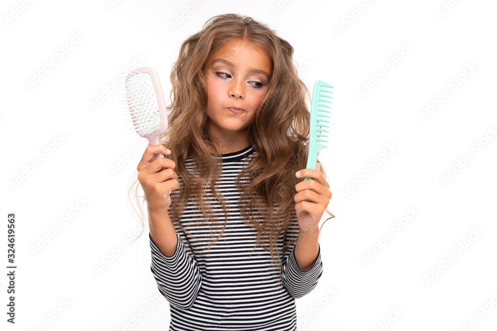 Young girl with beautiful brown hair chooses between two hair combs Young girl with beautiful brown hair chooses between two hair combs
