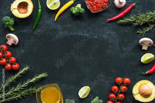 Black background with ingredients for Italian cuisine: tomatoes, mushrooms, broccoli, chilli peppers, avocado, rosemary, lime, olive oil and red sauce. Top view, flat lay, copy space.