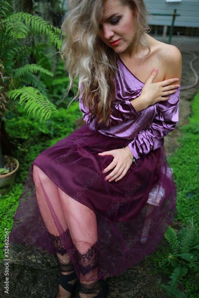 beautiful girl with long white hair in violet velvet top and lilac light fanin skirt enjoys nature in the garden beautiful girl with long white hair in violet velvet top and lilac light fanin skirt enjoys nature in the garden