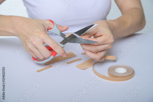 The faceless woman glues kinezio tape. Female hands close-up cut beauty applications for the face. An alternative to botox and hyaluronic acid. photo