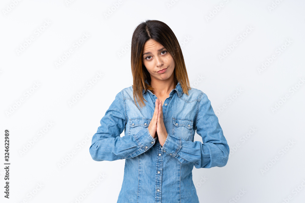 Young woman over isolated white background keeps palm together. Person asks for something Young woman over isolated white background keeps palm together. Person asks for something