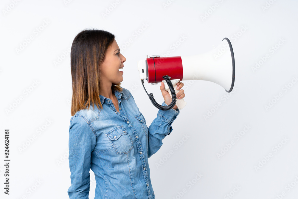 Young woman over isolated white background shouting through a megaphone Young woman over isolated white background shouting through a megaphone