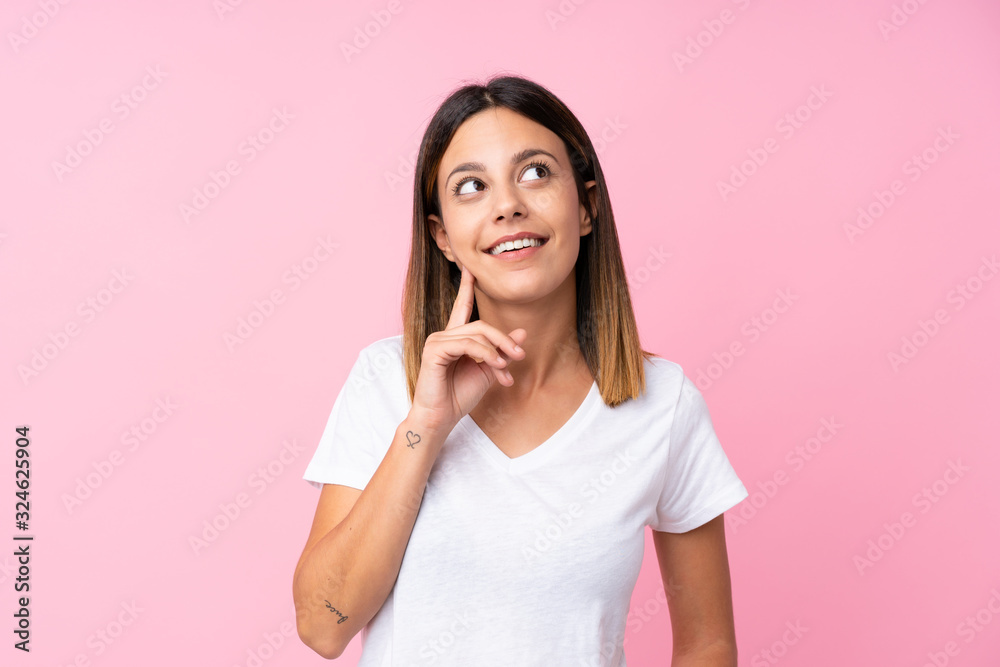 Young woman over isolated pink background thinking an idea while looking up Young woman over isolated pink background thinking an idea while looking up