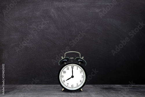 Time Management Concept : Retro black alarm clock showing eight o'clock with chalkboard background.