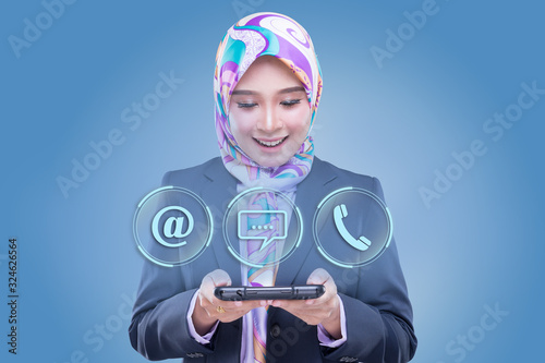 An attractive Muslim woman in office wear and hijab presenting 3 customer service support icons, email, live chat and call. Customer service or technical support landing page concept © HEMINXYLAN