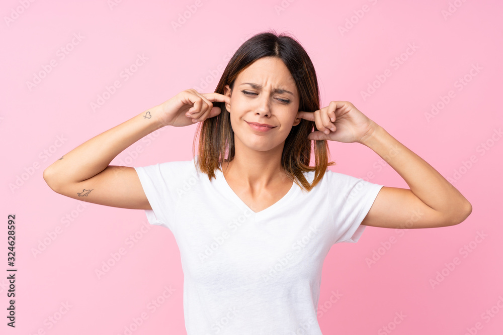 Young woman over isolated pink background frustrated and covering ears Young woman over isolated pink background frustrated and covering ears