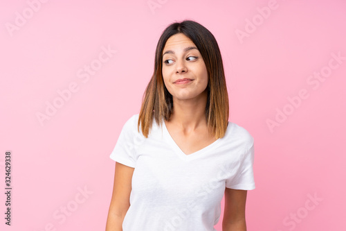 Young woman over isolated pink background making doubts gesture looking side
