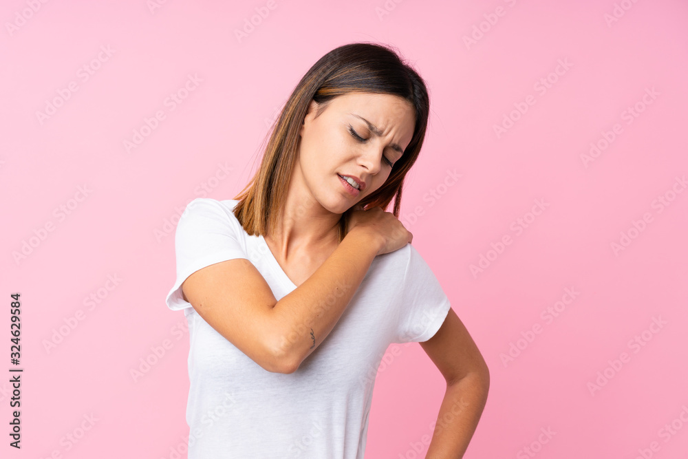 Young woman over isolated pink background suffering from pain in shoulder for having made an effort Young woman over isolated pink background suffering from pain in shoulder for having made an effort