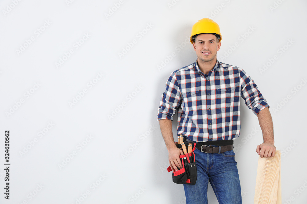 Handsome carpenter with wooden planks on light background. Space for text Handsome carpenter with wooden planks on light background. Space for text
