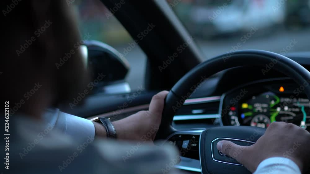 Close up view from back seat of businessman driving car transporting on city road following speed safety and rules sitting in automobile interior with display Digital dashboard. Lights in windshield Close up view from back seat of businessman driving car transporting on city road following speed safety and rules sitting in automobile interior with display Digital dashboard. Lights in windshield