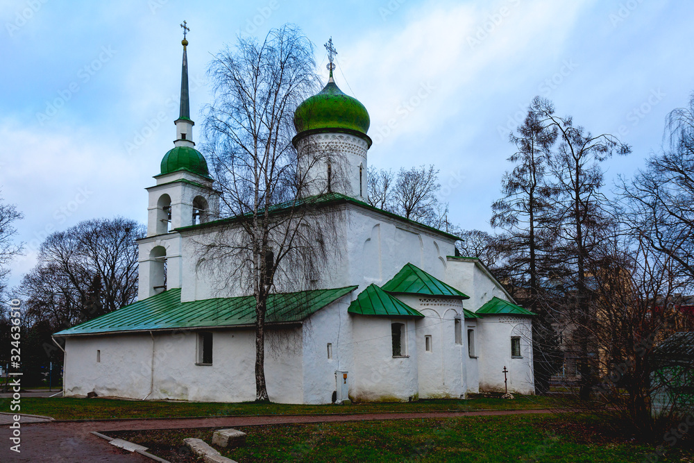 Old white stone Orthodox church with domes and a green roof against a cloudy sky Old white stone Orthodox church with domes and a green roof against a cloudy sky